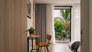 Una habitación de hotel moderna con comedor, una silla cómoda, un sofá y vistas a zonas verdes.