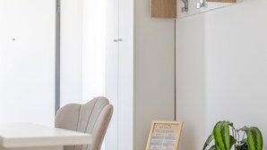 A modern room with a minimalist design, featuring a wooden cabinet with a built-in shelf, a framed informational sign, and a potted plant. - Double bed and sofa bed with private bathroom 3-4 people - 20 minutes from Milan (Trezzano sul Naviglio)