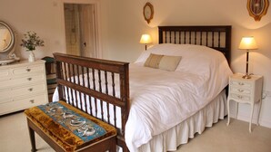 A bedroom with a large bed, wooden headboard, two bedside tables with lamps, a dresser, and a bench with a decorative cushion. - Set in the stunning grounds of Bayfield Hall (Bayfield)