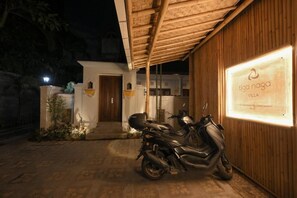 A motorcycle parked in front of a building with a sign that reads "tiga naga villa." - Villa Tiga Naga Sanur (Denpasar)