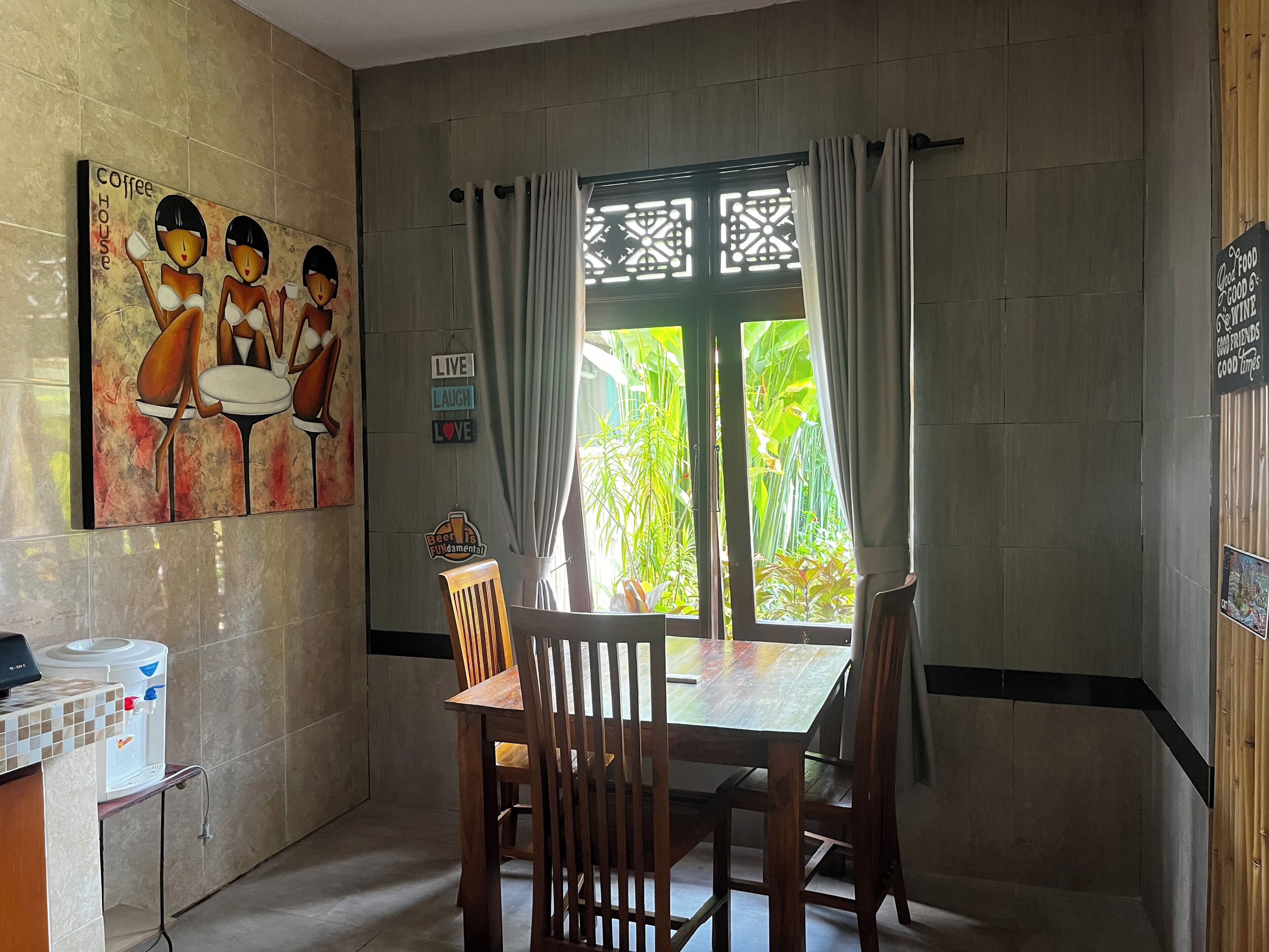 A dining area with a table and chairs, a water dispenser, and a painting on the wall.