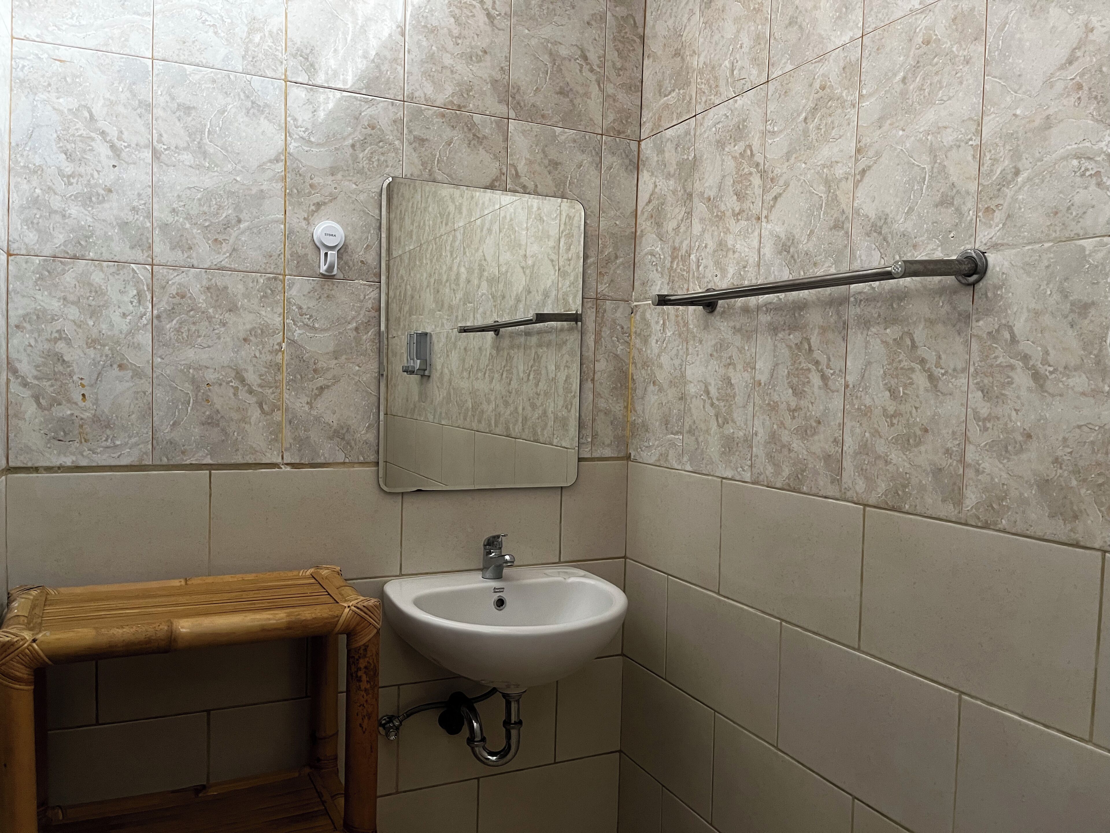Un baño con un lavamanos blanco, un espejo y un toallero.
