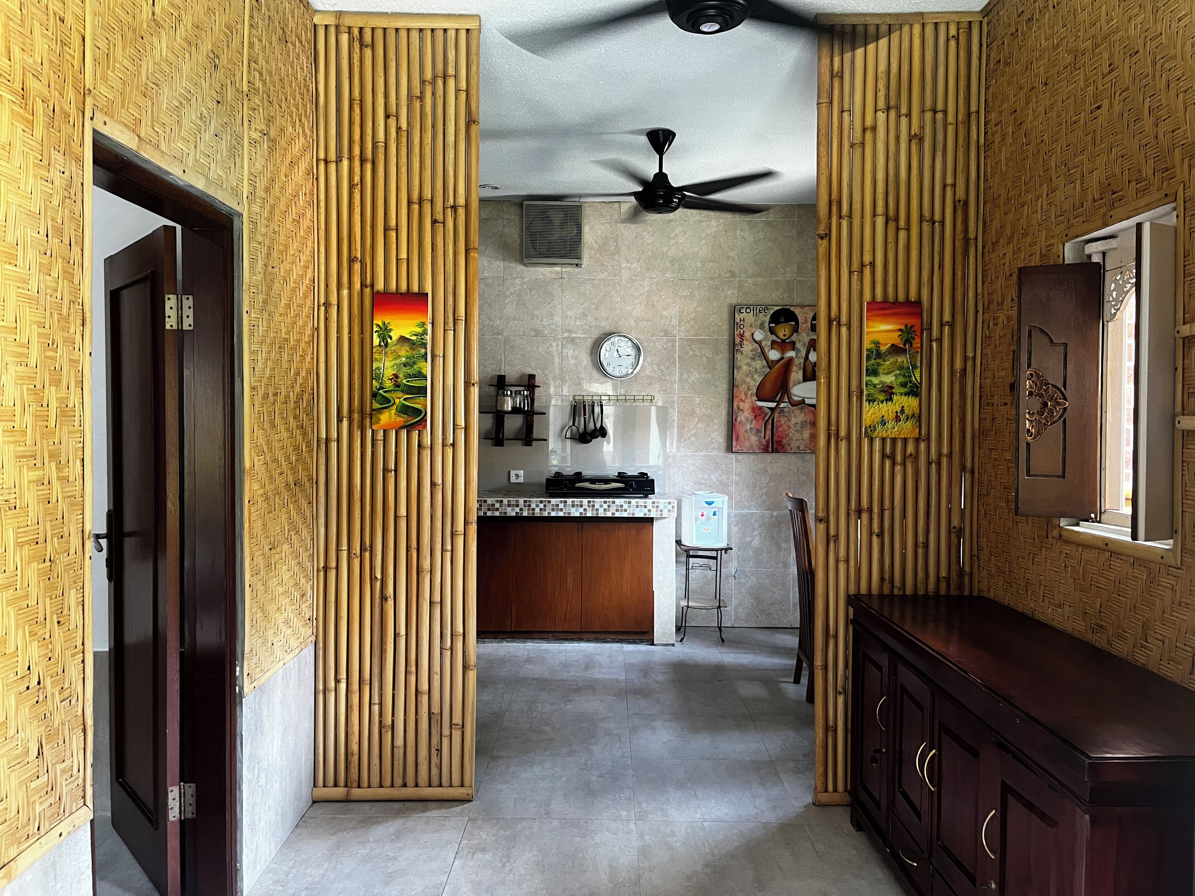 A modern kitchen with bamboo paneling, a ceiling fan, a coffee-themed painting, and a water dispenser.
