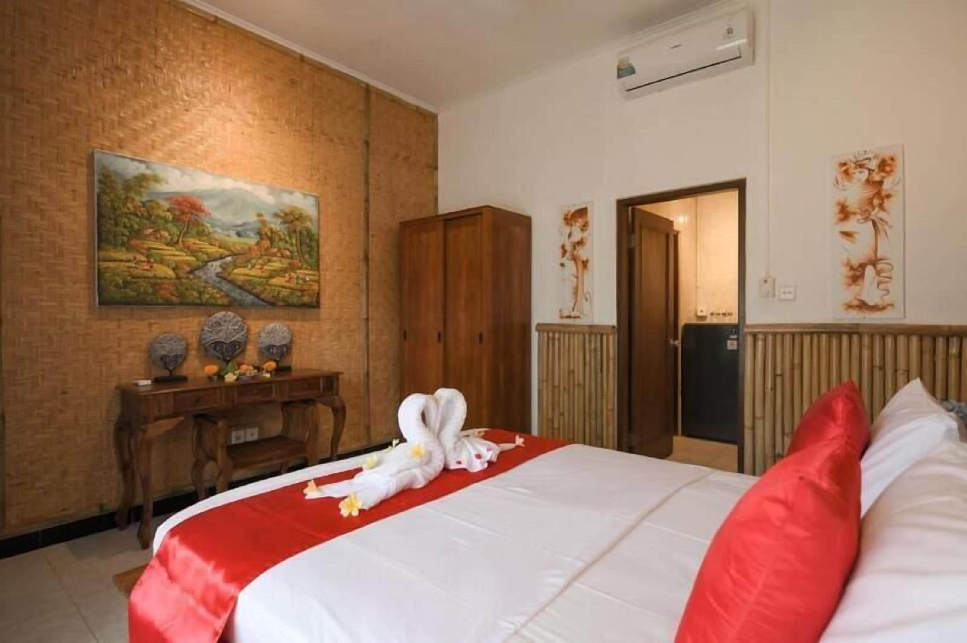 Una habitación de hotel con cama, un escritorio de madera, un cuadro y un armario.