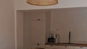 Uma sala de estar moderna com uma mesa de centro de vidro, cadeiras de vime e um lustre de palha.
