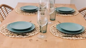 Mesa posta com pratos azul-turquesa, copos transparentes e um jogo americano trançado.