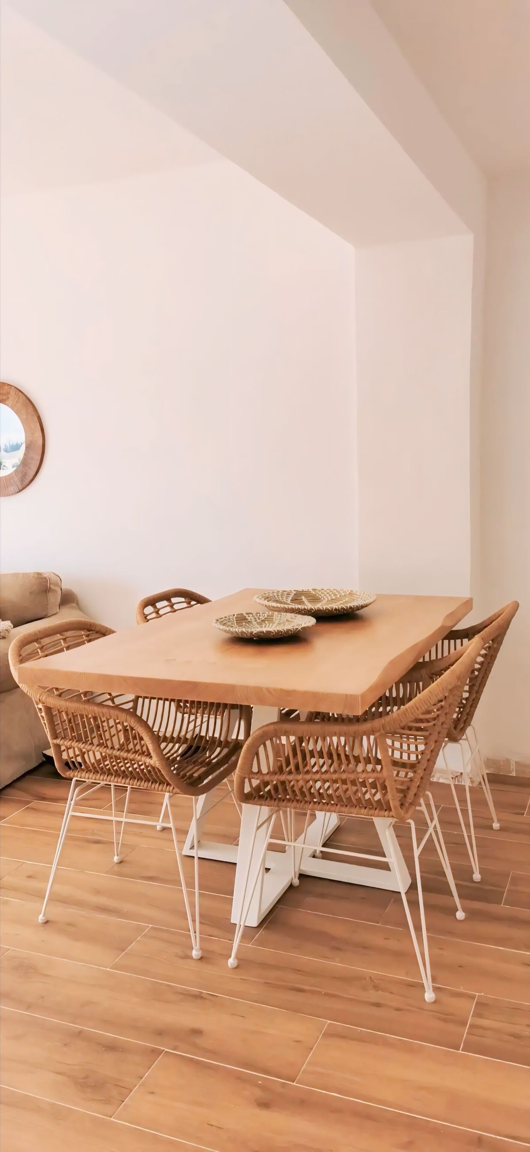 Un coin repas avec une table en bois et des chaises en osier.