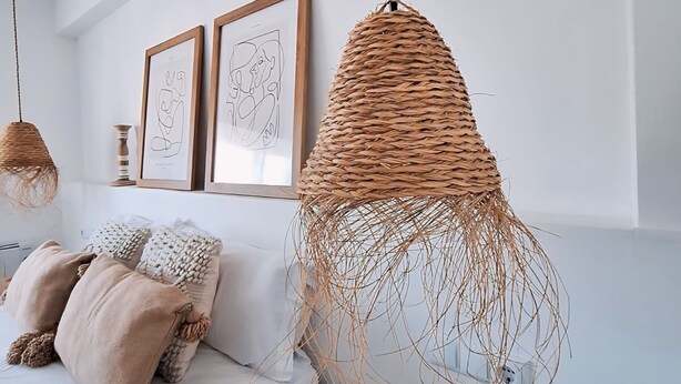 Quarto com cama, duas obras de arte emolduradas e uma luminária pendente de tecido.