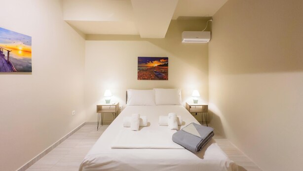 Ein Hotelzimmer mit einem großen Bett, zwei Nachttischen mit Lampen, einem Bild an der Wand und einer Klimaanlage.