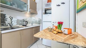 Una cocina con salpicadero de azulejos, un lavamanos de acero inoxidable, un horno doble y un refrigerador.