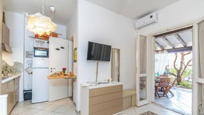 Una cocina moderna con horno empotrado, microondas y refrigerador. Fuera de la puerta hay una mesa de comedor de madera y sillas.