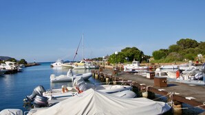 A marina with various boats docked, a wooden pier, and a clear blue sky. - Il Vecchio Faro Lilli (Loiri Porto San Paolo)