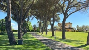 A pathway lined with trees leading to a building with a yellow facade. - Casale Antica Cassia Beauty Spa (Roma)