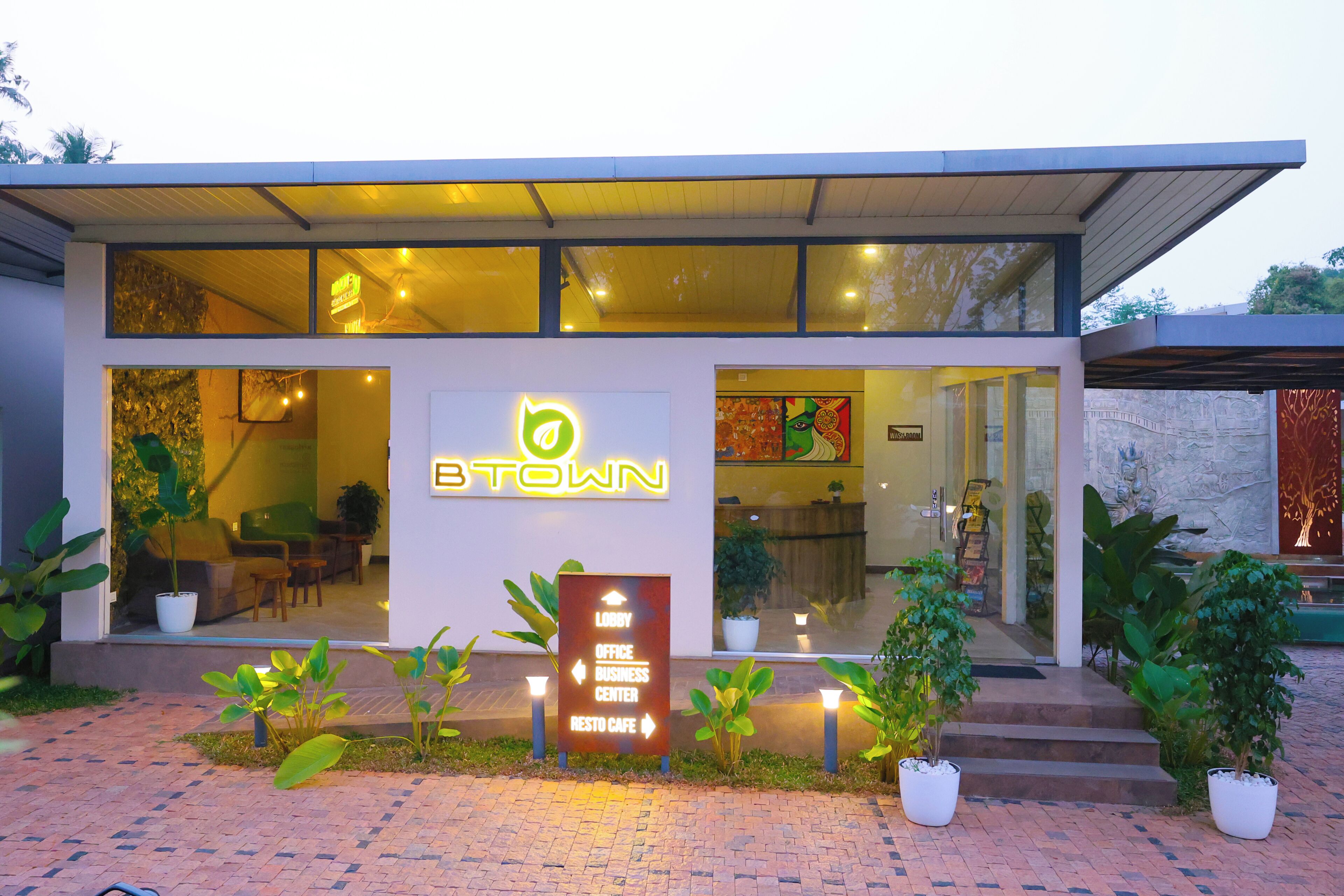 A modern building with a sign indicating a lobby, office, business center, and NESTO cafe.