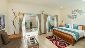 Een slaapkamer met een bed, een bank, een eettafel met fruit en uitzicht op een tuin door de schuifdeuren.