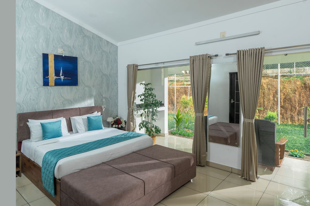 Une chambre moderne avec un grand lit, une vue sur le jardin et une porte coulissante.