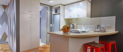 Una cocina moderna con una isla curva, taburetes rojos y un frutero.