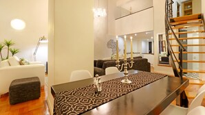 A modern living room with a dining area, featuring a dark wooden table, patterned runner, and a chandelier. - Cape Eazi Stayz Mutual Heights (Cape Town)