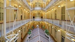 A multi-level atrium with a central staircase, glass railings, and hanging lights. - Cape Eazi Stayz Mutual Heights (Cape Town)