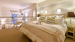 A hotel room with a large bed, bedside tables, a mirror, and a view of the city. - Cape Eazi Stayz Mutual Heights (Cape Town)