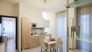 Cozinha moderna com armários de madeira, micro-ondas e área de jantar com mesa e cadeiras.