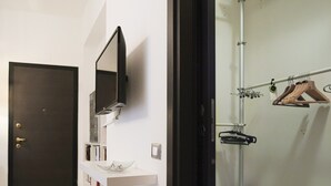 Casa de banho moderna com porta escura, lavatório branco, espelho e zona de duche com um porta-toalhas.