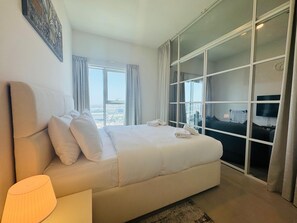 Una camera d'albergo con un letto grande, una TV e vista sulla città attraverso ampie vetrate.