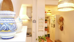 A kitchen with white cabinets, a wooden cabinet, and a hanging light fixture.