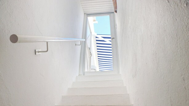 A white staircase leading to a door with a window.