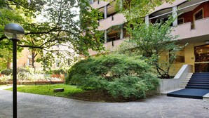 Un pati amb un camí de pedra, un arbust petit i un edifici que té una escala.