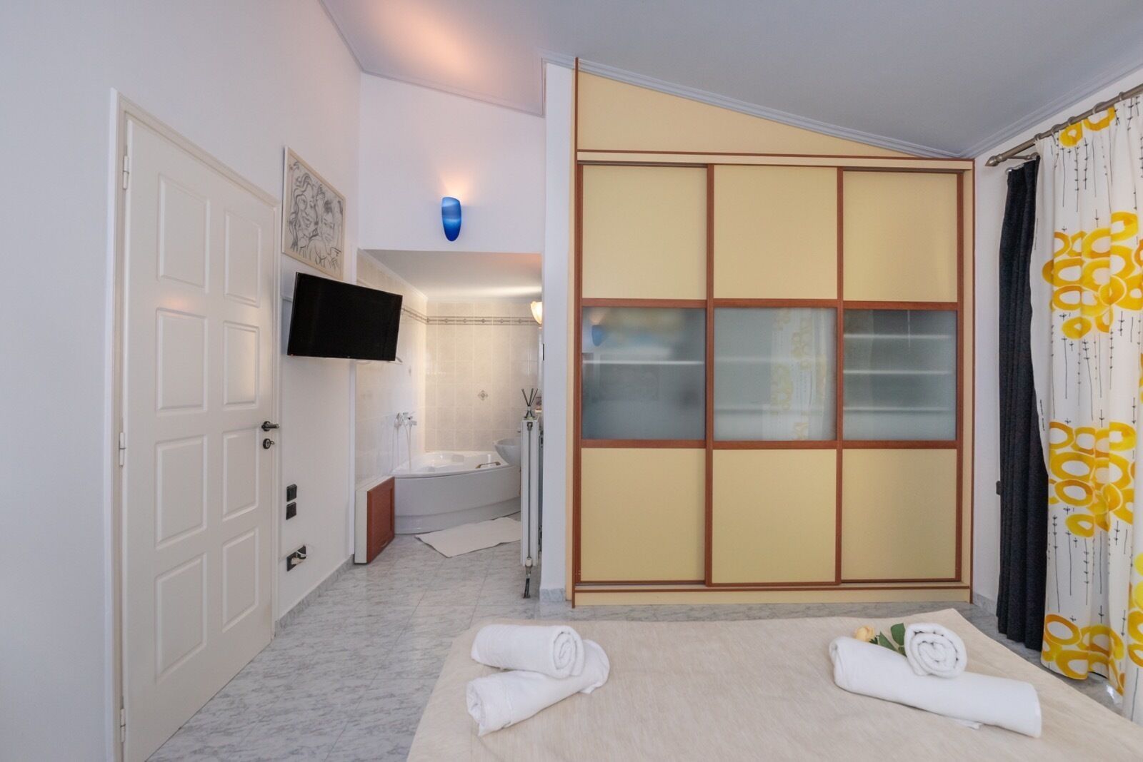 Ein Hotelzimmer mit einer verschiebbaren Shoji-Schirmwand, einer Badewanne, einer Toilette, einem Waschbecken, einem Flachbildfernseher und Handtüchern auf dem Boden.