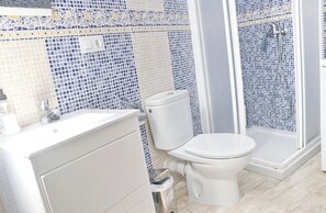 A bathroom with a white sink, toilet, and shower.
