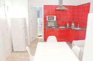 Une cuisine moderne avec des carreaux rouges, des armoires blanches, un four à micro-ondes et un grille-pain.