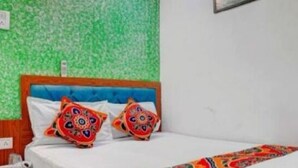 A bed with a blue headboard, two decorative pillows, and a patterned bedspread. - Hotel  Super  (Mumbai)