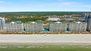 A beachfront hotel with multiple high-rise buildings, each featuring balconies and a pool area.