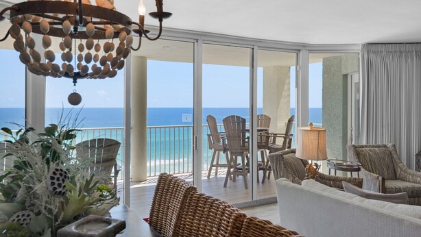 A balcony with wicker furniture, a chandelier, and a view of the ocean.