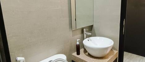Un bagno moderno con un water bianco, un lavandino e uno specchio.