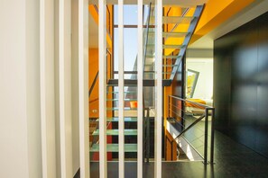 A modern interior with a glass staircase, metal railings, and a view of a room with a bed and a window. - Villa Leonor Cliffside Retreat (Calheta)