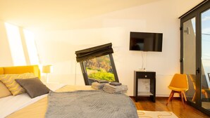 A modern bedroom with a bed, a TV, a desk, and a chair. - Villa Leonor Cliffside Retreat (Calheta)