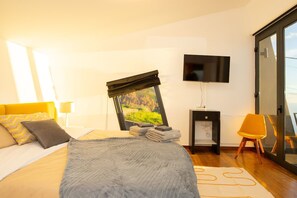 A modern bedroom with a bed, a TV, a desk, and a chair. - Villa Leonor Cliffside Retreat (Calheta)