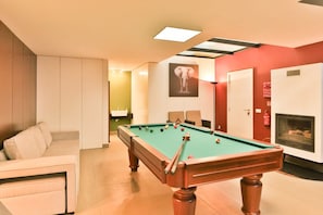 A pool table in a room with a sofa, a fireplace, and a framed picture on the wall. - Villa Leonor Cliffside Retreat (Calheta)