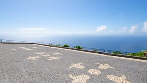 A paved area with a railing and a view of the ocean. - Villa Leonor Cliffside Retreat (Calheta)