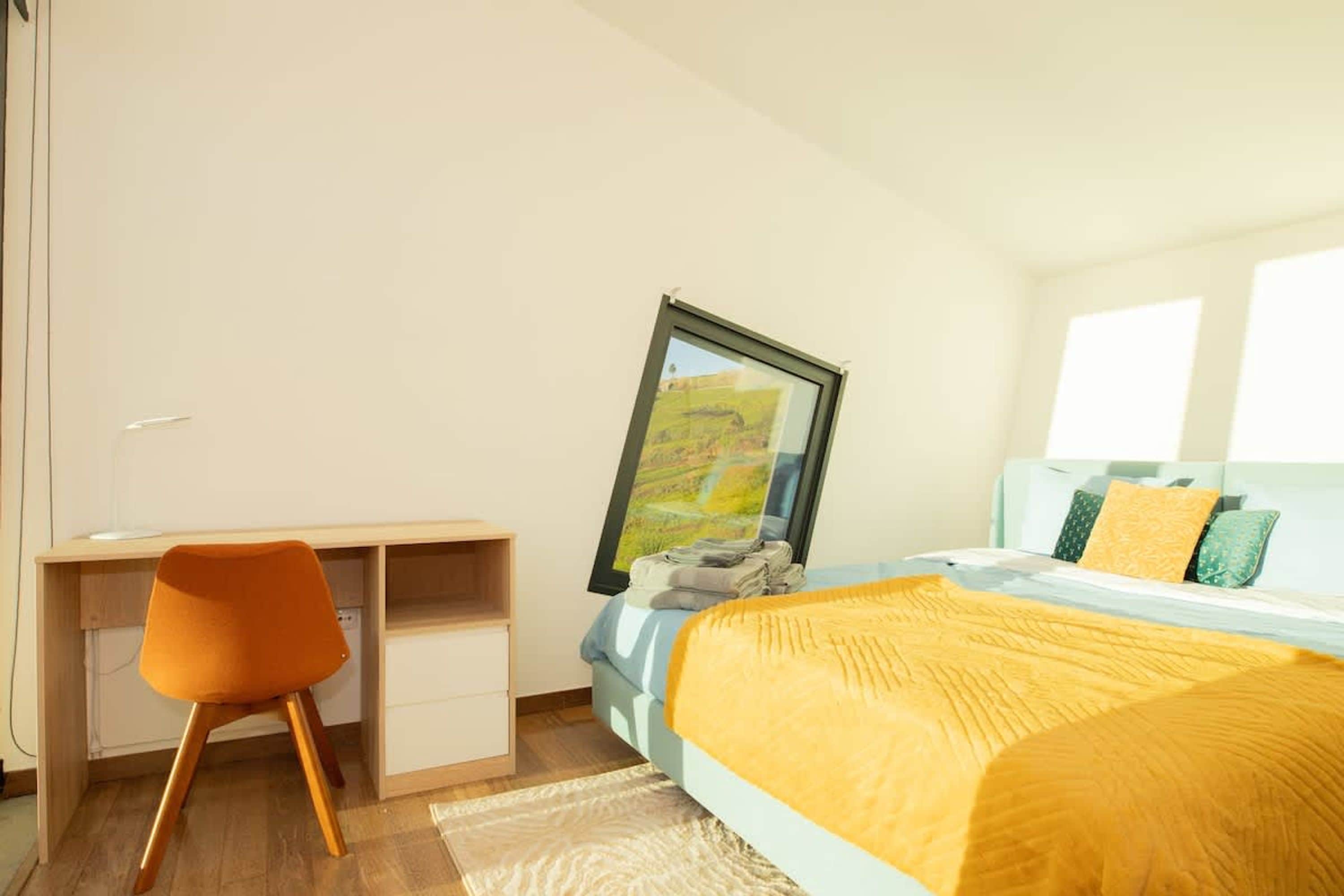 A bedroom with a bed, a desk, and a chair.