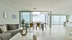 Un vaste espace de vie comprenant un canapé moderne, une table basse et une table à manger pouvant accueillir six personnes.