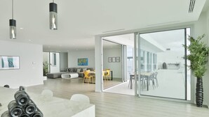 Un intérieur moderne comprenant un coin repas, un canapé et une grande porte vitrée donnant sur un espace extérieur.