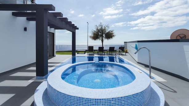 A rooftop pool with a clear view of the sky and palm trees. - Villa Andrade Ocean View (Funchal)
