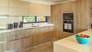 Una cocina moderna con armarios de madera, un horno de acero inoxidable y un ventanal con vistas a zonas verdes.