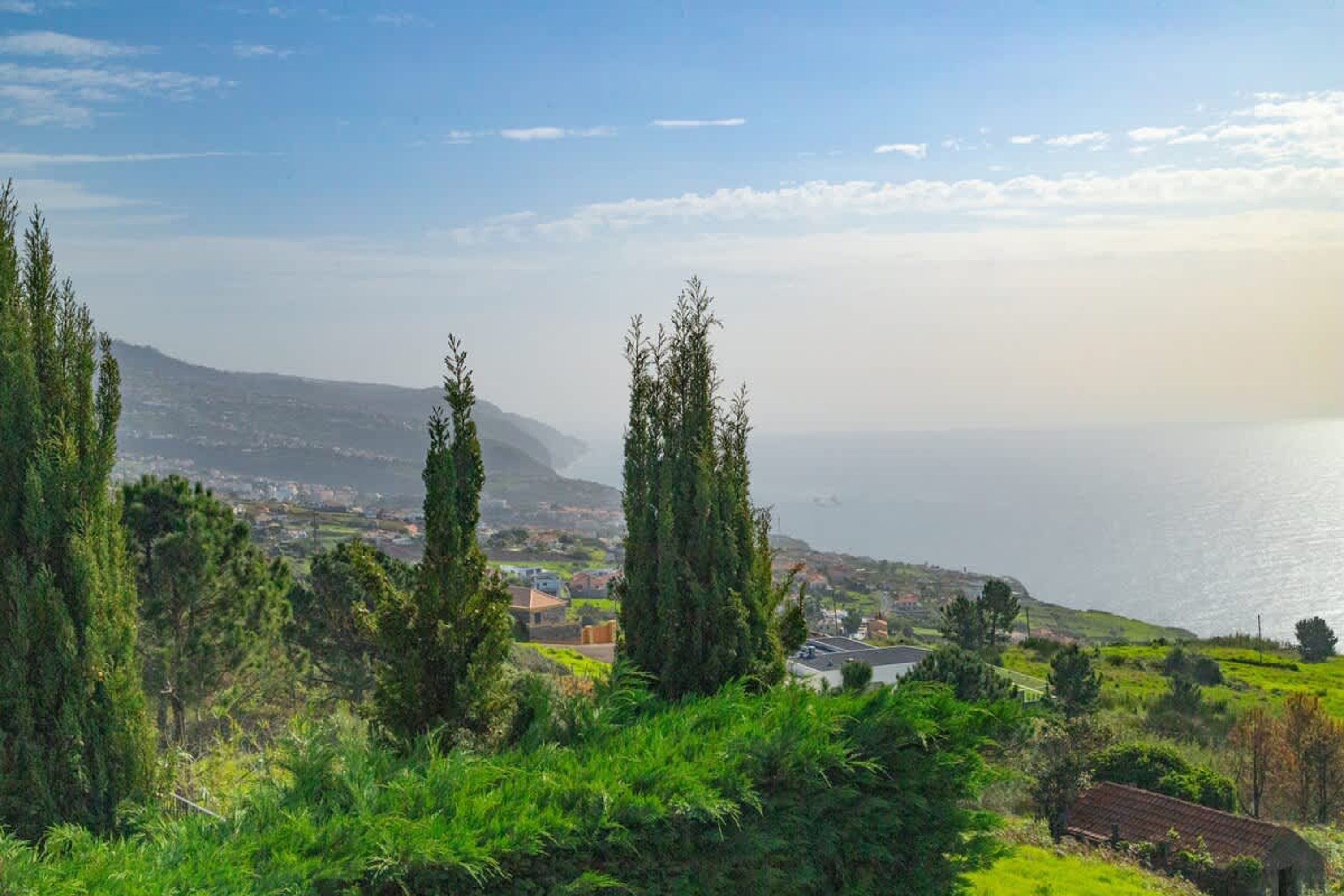 Un paysage côtier offrant une vue sur la mer et les collines lointaines.