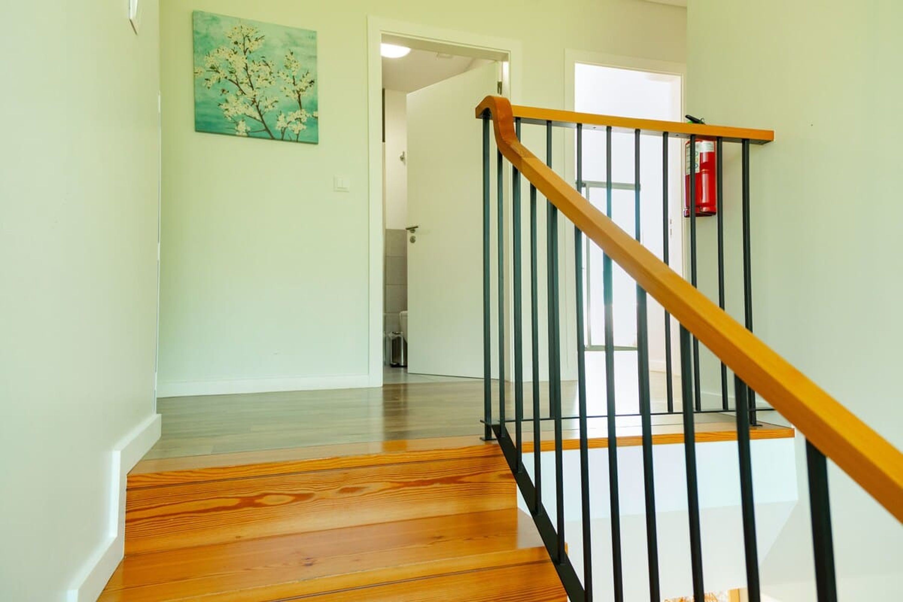 A wooden staircase with black railings leading to a room with white walls and a door.