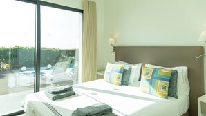 Una habitación de hotel con una cama grande, vista a una piscina y un balcón.